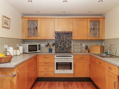 A kitchen with wooden cabinets a microwave an oven and a sink at Sherway Shippen in Clyst Hydon near Bradninch