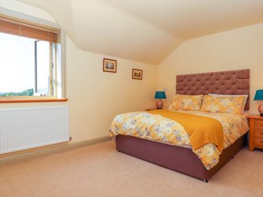 A bedroom with a double bed yellow floral bedding two bedside tables and an open window at Sherway Shippen in Clyst Hydon near Bradninch
