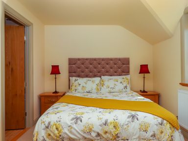 A bedroom with a floral bedspread and two red lamps on wooden bedside tables at Sherway Shippen in Clyst Hydon near Bradninch
