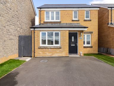 A front view of a two-story brick house with a black door and white windows at 69 Ffordd Y Meillion in Llanelli
