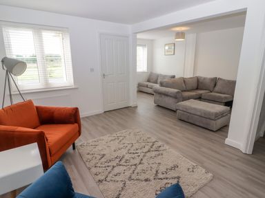 A living room with an orange armchair blue cushion beige rug and gray sofa at 69 Ffordd Y Meillion in Llanelli