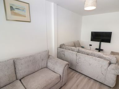 A living room with two light gray sofas a wall mounted television and a framed picture at 69 Ffordd Y Meillion in Llanelli