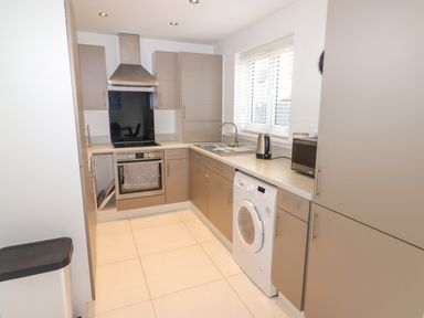 A kitchen with a washing machine oven stove sink kettle and microwave at 69 Ffordd Y Meillion in Llanelli