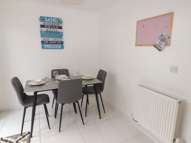 A dining area with a table set for four with grey chairs and wall decorations at 69 Ffordd Y Meillion in Llanelli