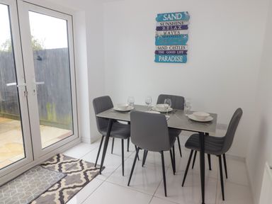 A dining area with a table set for four and glass doors showing an outdoor space at 69 Ffordd Y Meillion in Llanelli