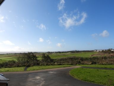 An outdoor view of a paved path and grassy fields with houses in the distance at 69 Ffordd Y Meillion in Llanelli
