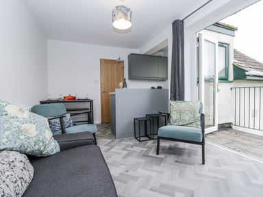 A living room with a sofa, armchair and kitchen counter at Claife Flights, Bowness-On-Windermere