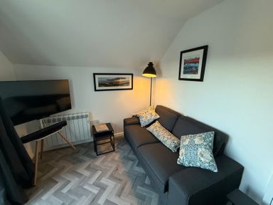 A living room with a television and sofa at Claife Flights in Bowness-On-Windermere