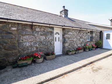 An exterior view of a stone cottage with potted plants at Ysgubor Newydd Parc Isaf Dyffryn Ardudwy
