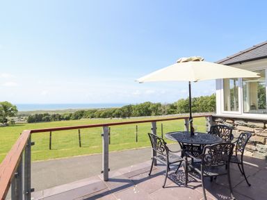 An outdoor seating area with a table and umbrella at Ysgubor Newydd Parc Isaf Dyffryn Ardudwy
