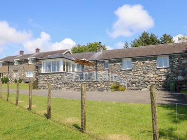 A stone house with a deck and grass area at Ysgubor Newydd Parc Isaf Dyffryn Ardudwy