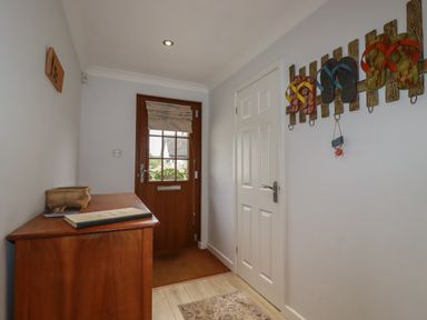 An entryway with a wooden door a chest of drawers a white door and flip flop wall decorations at 3 The Bowling Green in St Just in Roseland near St Mawes