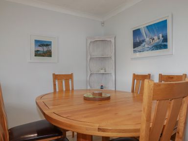 A dining room with a wooden table and chairs and framed pictures on the walls at 3 The Bowling Green in St Just in Roseland near St Mawes