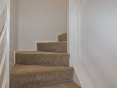A carpeted staircase with white walls and railing at 3 The Bowling Green in St Just in Roseland near St Mawes