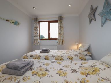 A bedroom with two single beds with floral bedding and towels on top at 3 The Bowling Green in St Just in Roseland near St Mawes