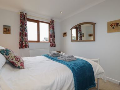 A bedroom with a double bed floral curtains and dog pictures on the walls at 3 The Bowling Green in St Just in Roseland near St Mawes
