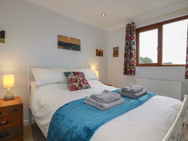 A bedroom with a double bed with white bedding and blue throw at 3 The Bowling Green in St Just in Roseland near St Mawes