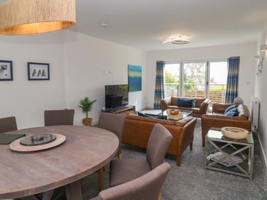 A living room with a sofa and dining area at Miramar in St. Ives