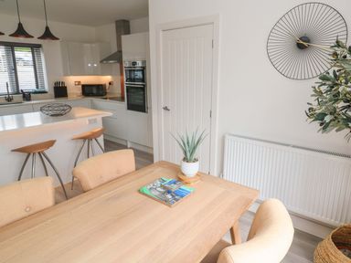 A dining area featuring a table with chairs and kitchen appliances at Miramar St. Ives