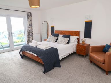 A bedroom with a bed and armchair at Miramar in St. Ives