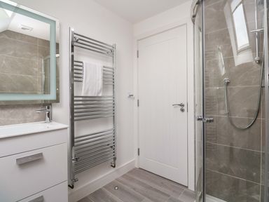 A bathroom with a sink, mirror, shower, and towel rail at Miramar in St. Ives
