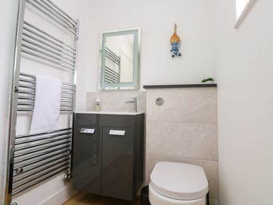 A bathroom with a towel radiator, sink, mirror, and toilet at Miramar in St. Ives