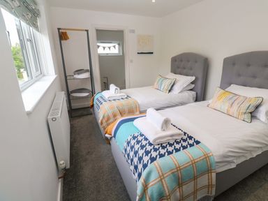 A bedroom with two beds and a wardrobe at Miramar in St. Ives
