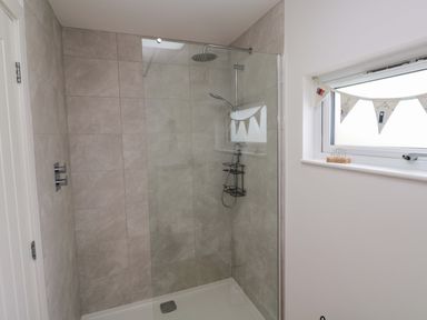 A shower with glass enclosure and tiled wall at Miramar in St. Ives