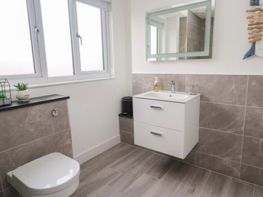 A bathroom with a sink, toilet, and mirror at Miramar in St. Ives