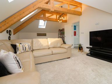 A living room with a sofa and television at Miramar in St. Ives