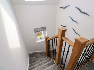 A staircase with a handrail and window at Miramar in St. Ives