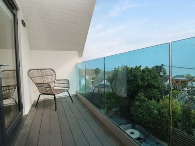 A balcony with a chair and glass railing at Miramar in St. Ives