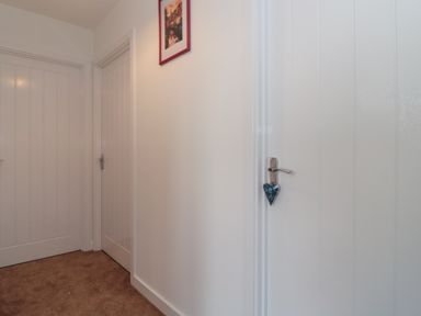 A hallway with three closed white doors and a framed picture on the wall at Cotswold Outlet Coach House in Tewkesbury