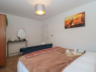 A bedroom with a bed covered with a brown blanket and a tray with a mug and magazine on it at Cotswold Outlet Coach House in Tewkesbury