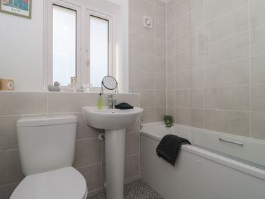 A bathroom with a toilet sink and bathtub with tiled walls and a window at Cotswold Outlet Coach House in Tewkesbury