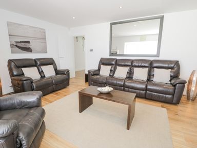 A living room with leather sofas coffee table and large mirror at The Gables in Tywyn