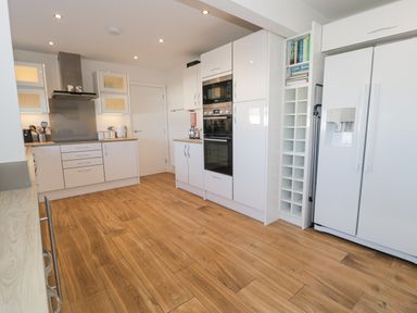 A kitchen with white cabinets wooden floor double door refrigerator and built in oven at The Gables in Tywyn