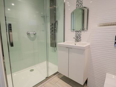 A bathroom with a glass shower enclosure and a white vanity with a mirror above at The Gables in Tywyn