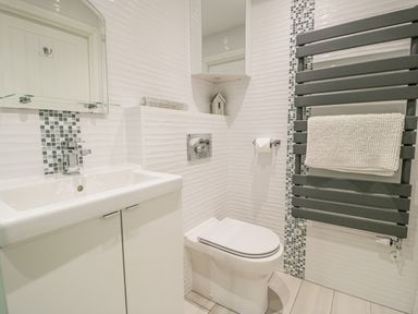 A bathroom with a sink cabinet a toilet a heated towel rail and a mirror at The Gables in Tywyn
