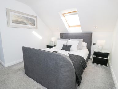 A bedroom with a gray bed and white pillows under a skylight at The Gables in Tywyn
