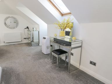 A room with mirrored furniture including a dressing table and chest of drawers a skylight window and grey carpet at The Gables in Tywyn