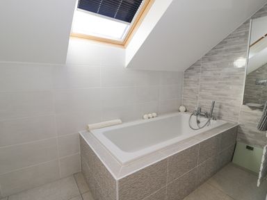 A bathroom with a bathtub under a skylight window at The Gables in Tywyn