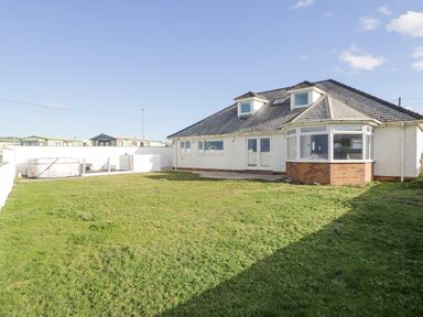 A house with a tiled roof and a lawn in the backyard at The Gables in Tywyn