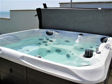 An outdoor hot tub filled with water on a terrace with a sea view at The Gables in Tywyn