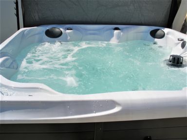 A bubbling outdoor hot tub with headrests and water jets at The Gables in Tywyn