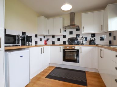 A kitchen with white cabinets a microwave oven and a kettle at Gwanda Tregolds near St Merryn