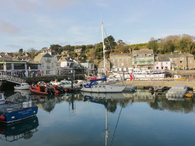 A harbor with various boats docked near buildings and houses at Gwanda in Tregolds near St Merryn