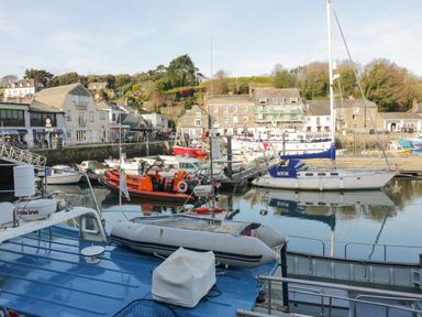 A harbor with several boats docked and buildings along the waterfront at Gwanda in Tregolds near St Merryn