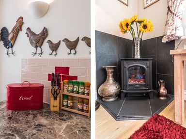 A kitchen countertop with a red bread box knives and spice jars and a corner space with a black stove a vase with sunflowers and decorative metal pots at October House Holiday Cabin Damerham