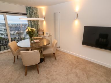 A dining area with round table and four chairs near a balcony door with outdoor seating at Fal View in Falmouth